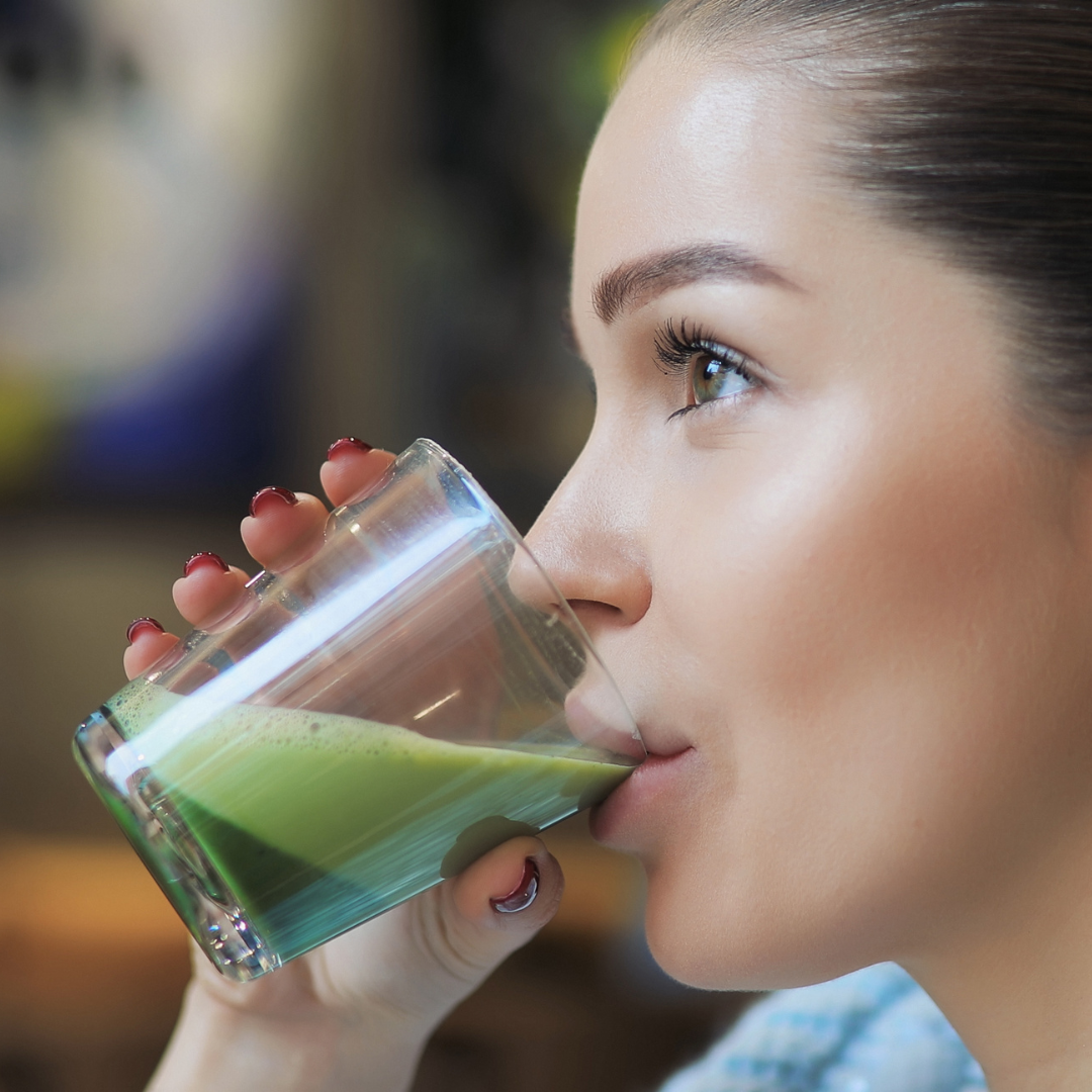 person drinking matcha out of a glass cup